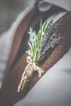 a boutonniere with lavenders and leaves on the lapel of a man