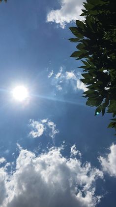 the sun shines brightly through the clouds in the blue sky above some green leaves