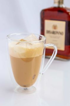 a glass cup filled with liquid next to a bottle