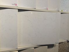 white marble tiles are lined up on the shelves in a store, with different colors and sizes