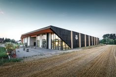 a black building sitting on top of a dirt road next to a field and trees