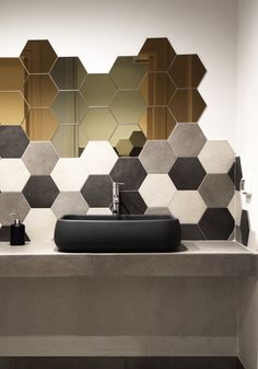 a modern bathroom with hexagonal tiles on the wall and black sink below it