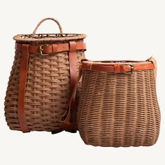 two wicker baskets sitting next to each other on top of a white surface with brown leather straps