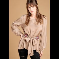 Taupe Floral Embroidered Waist Tie Blouse. Loose Fit Long Sleeves, Round Neck, A Back Keyhole And A Floral Embroidered Waist Tie. 50% Rayon, 50% Cupro Beige Long Sleeve Tops For Festive Occasions, Elegant Floral Embroidered Top For Fall, Elegant Spring Blouse With Embroidered Hem, Festive Chic Embroidered Blouse, Elegant Embroidered Top For Spring Festivals, Chic Floral Embroidered Blouse For Fall, Chic Floral Embroidery Blouse For Fall, Festive Fall Blouse With Floral Embroidery, Fall Festive Floral Embroidered Blouse