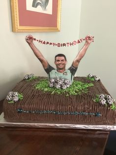 a man sitting on top of a cake with his arms in the air and hands up