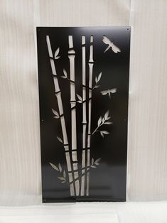 a metal wall hanging with bamboo trees and birds on it's side, in front of a white background