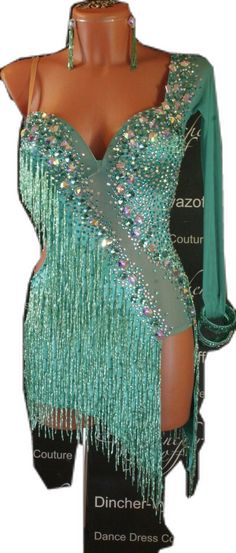 a woman's green dress with fringes and beads on the bottom, in front of a mannequin