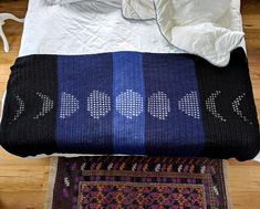 a blue and black blanket sitting on top of a wooden floor next to a bed