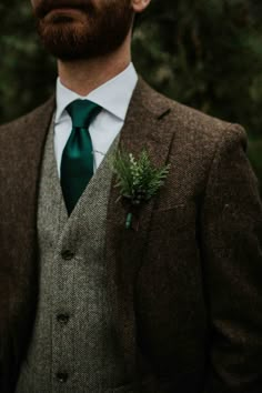 a man wearing a suit and tie with a green flower in his lapel pocket