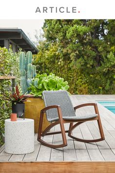 a rocking chair next to a pool with succulents in the back ground