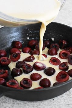 a pan filled with yogurt and cherries being poured into the skillet