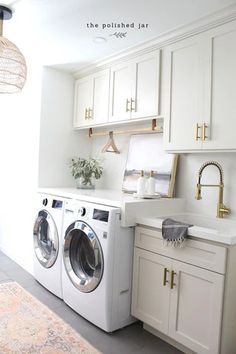 a washer and dryer in a white kitchen with gold hardware on the doors