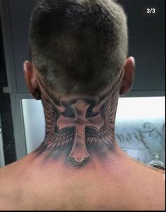 the back of a man's neck with a cross and wings tattoo on it