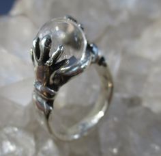 "This is a Hand Cast Sterling Silver Ring with a unique \"Crystal Ball\" design. It is set with a 10 mm Natural Quartz Crystal Ball. This original design has two hands holding the crystal ball. Unique ring, surely will be noticed everywhere you go. The ring is about 7/16 inch wide on top and tapers to a plain shank in the back. It is 7/16 inch tall. Truly Magical ! This ring is made in a size 7 1/4. I will wrap the ring in a gift box and mail in a small box within 1-2 days of purchase, usually o Formal Sterling Silver Crystal Ring With Round Stone, Formal Sterling Silver Crystal Ring With Round Cut, Mystical Sterling Silver Crystal Ring, Spiritual Sterling Silver Crystal Ring For Formal Events, Mystical Silver Crystal Ring, Spiritual Sterling Silver Crystal Ring For Formal Occasions, Unique Clear Rings, Unique Clear Round Rings, Formal Clear Jewelry With Polished Finish