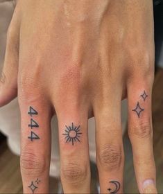 two people with tattoos on their fingers, one has a sun and the other has an arrow