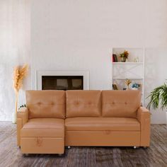 a tan leather couch sitting in front of a fire place next to a potted plant