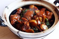 a bowl filled with meat and vegetables on top of a wooden table