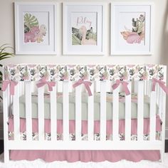 a white crib with pink bedding and pictures on the wall