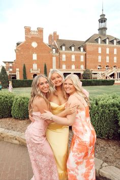 three beautiful women standing next to each other in front of a building