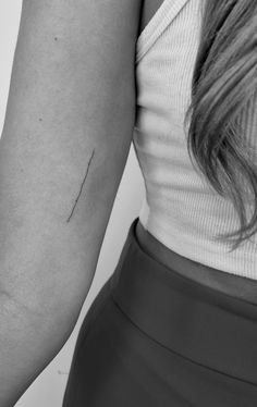 a woman's arm with an arrow tattoo on the left side of her arm