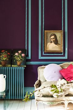 a living room with purple walls and paintings on the wall, including an old chair