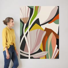 a woman standing next to a painting on the wall