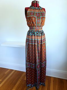 "Bust 36\" Waist 25-26\" Hip max 50\"  Length 52\"  Labels: None, likely homemade  Fabulous 1970s geometric floral print maxi! Beautiful color pallete, chocolate brown with pops of pink and turquoise. Really nice, silky feel fabric with a ribbed texture. High neck halter and back metal zipper. The sizing on this one is pretty specific. Very firm at waist, maximum snug 26\". However the minimum bust is about 36\" to keep the back up properly. Unlined, it is very lightweight but still opaque. In really beautiful vintage  condition with no known flaws." Retro Multicolor Printed Maxi Dress, Sleeveless Printed Brown Maxi Dress, Brown Sleeveless Printed Maxi Dress, Hippie Brown Floral Print Dress, Fitted Vintage Brown Maxi Dress, Brown Fitted Hippie Dress, Brown Floral Print Sleeveless Maxi Dress, Sleeveless Brown Floral Print Maxi Dress, Multicolor Vintage Maxi Dress With Boho Print