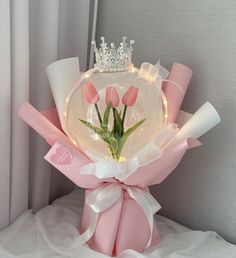 a bouquet of tulips with a tiara on top is sitting on a bed