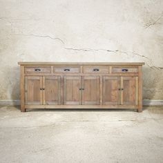 a large wooden cabinet sitting on top of a cement floor next to a white wall