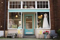 a dress shop with chairs and tables in front of the storefront window, decorated with mannequins