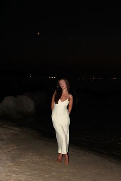 a woman is standing on the beach at night