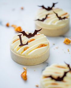 three desserts with white frosting and chocolate decorations