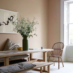 a room with a bench, table and flowers in the vase on the wall next to it