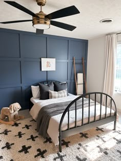 a bed room with a neatly made bed and a ceiling fan above it's headboard