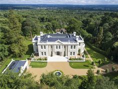 an aerial view of a large white house in the middle of trees and grass area