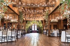 the inside of a barn with tables and chairs set up for an elegant wedding reception