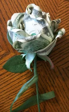 a flower made out of money sitting on top of a wooden table