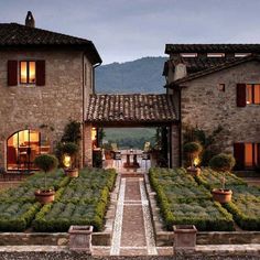 an outdoor garden with potted plants in front of two stone buildings at night time