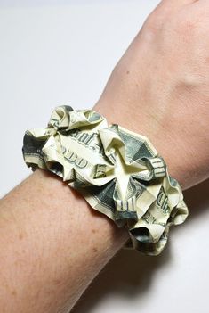 a person's arm with a bracelet made out of dollar bills on the wrist