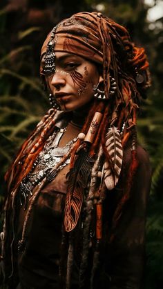 a woman with dreadlocks and tattoos on her face is standing in the woods