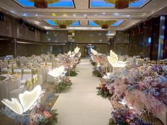 a banquet hall with tables and chairs covered in white linens, decorated with floral centerpieces