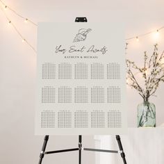 a wedding seating chart is displayed on a easel next to a vase with baby's breath flowers