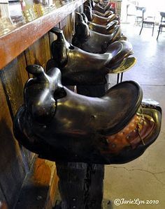 row of horse shoes lined up on the wall in front of a bar with stools