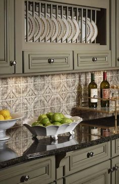 a kitchen with green cabinets and granite counter tops, wine glasses on the cabinet doors