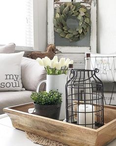 a tray with flowers and candles in it sitting on a table next to a couch