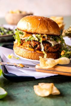 a chicken sandwich with lettuce and coleslaw on a plate next to chips