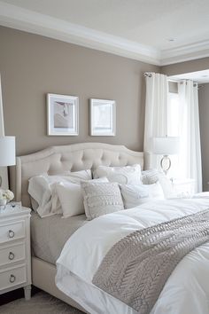 a white bed sitting in a bedroom next to two pictures on the wall above it