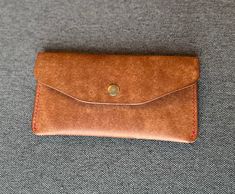 "The Jeanne - This handmade clutch is made with two pockets and has a leather divider and card slot. This handmade wallet is made with a full-grain vegetable tanned Pueblo leather from a tannery called Badalassi Carlo in Italy. It is hand-stitched with Vinymo polyester waxed thread in the color Burgundy. The interior of the clutch is hand-stamped with our Lee's Leather logo and its edges are hand-finished with Tokonole. It has a snap enclosure in silver. This clutch is sure to patina beautifully and last for years to come! The dimensions of this wallet are H 7.125\" x W 3.75\" x D .50\" and it weighs approximately 2.5 ounces. Lee's Leather goods are crafted in Northern Idaho.  Check out Lee's Leather on Instagram: @lees.leather" Handmade Brown Clutch Wallet, Handmade Brown Wallet For Daily Use, Everyday Handmade Brown Clutch, Handmade Brown Coin Purse For Everyday Use, Handmade Clutch Wallet For Everyday Use, Brown Hand-stitched Coin Purse For Daily Use, Hand-stitched Brown Coin Purse For Daily Use, Handmade Envelope Wallet, Everyday Brown Vegetable-tanned Wallet