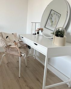 a white desk with a mirror, chair and potted plant