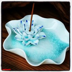 a blue and white bowl with a flower in it sitting on a table next to a wooden stick